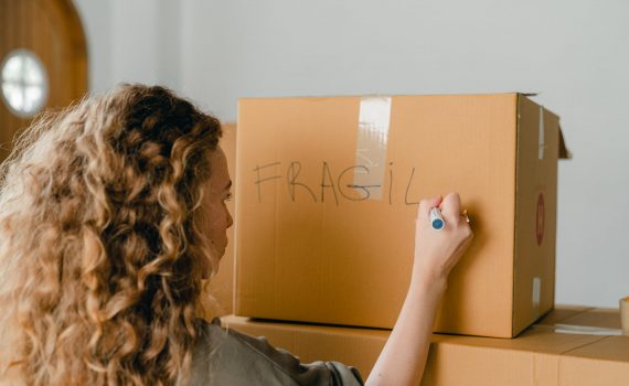 unrecognizable woman writing note on carton box with marker