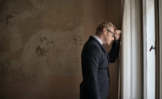 desperate evicted male entrepreneur standing near window