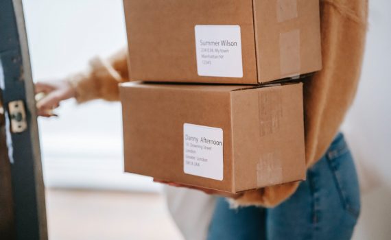 crop unrecognizable woman carrying boxes and entering post office