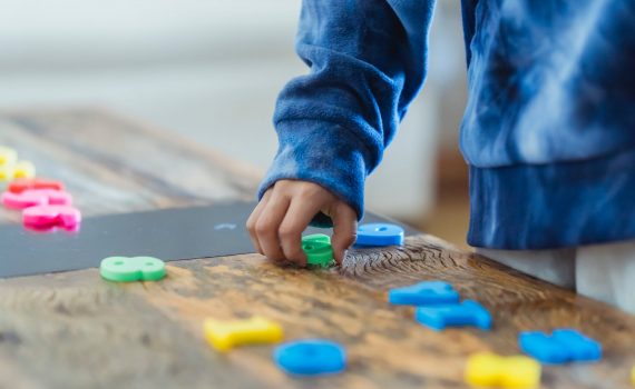 ethnic kid making row of toy numbers