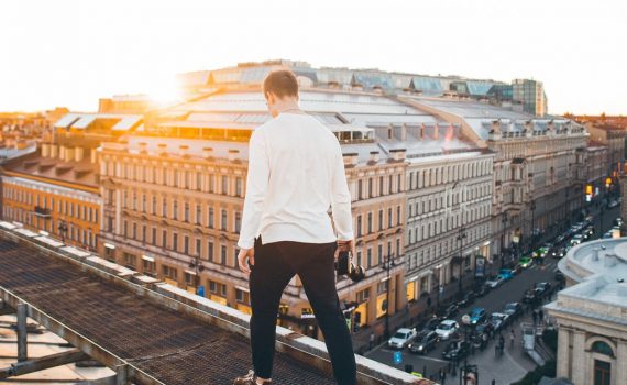 man in white long sleeve shirt and black pants standing on top of a building during