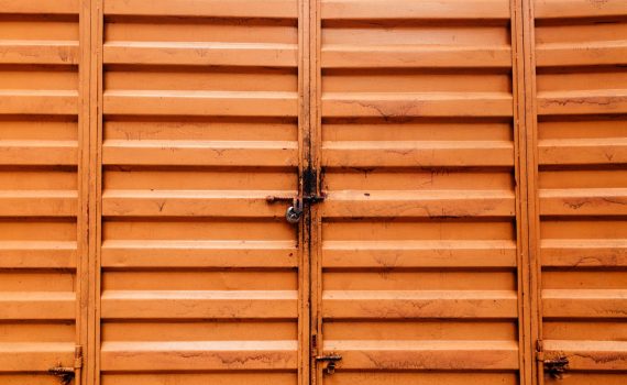 dirty surface of a padlocked orange metal doors