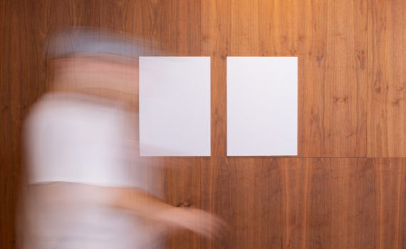 unrecognizable person walking near wall with empty papers