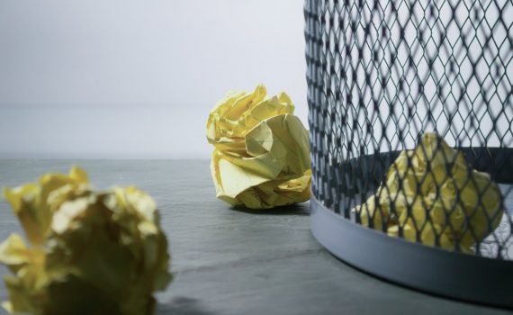 focus photo of yellow paper near trash can