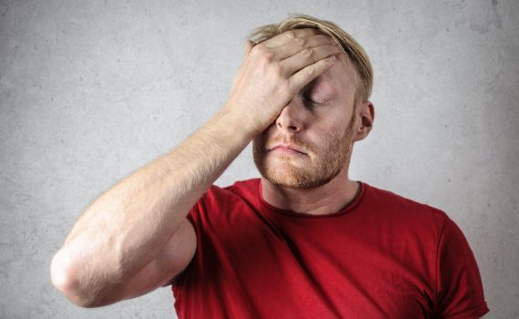 a man in red shirt covering his face