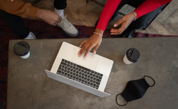 unrecognizable black colleagues browsing laptop at table with face mask