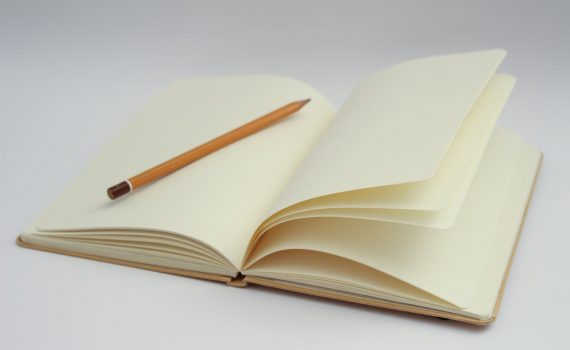 white notebook and yellow pencil