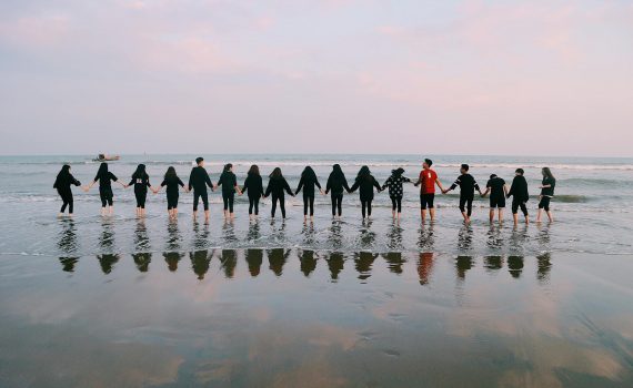 team holding their hands on seashore