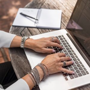 person typing on MacBook Pro on brown wooden table during daytime photo